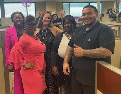 Members of our Client Services Team smiling in their cubicles