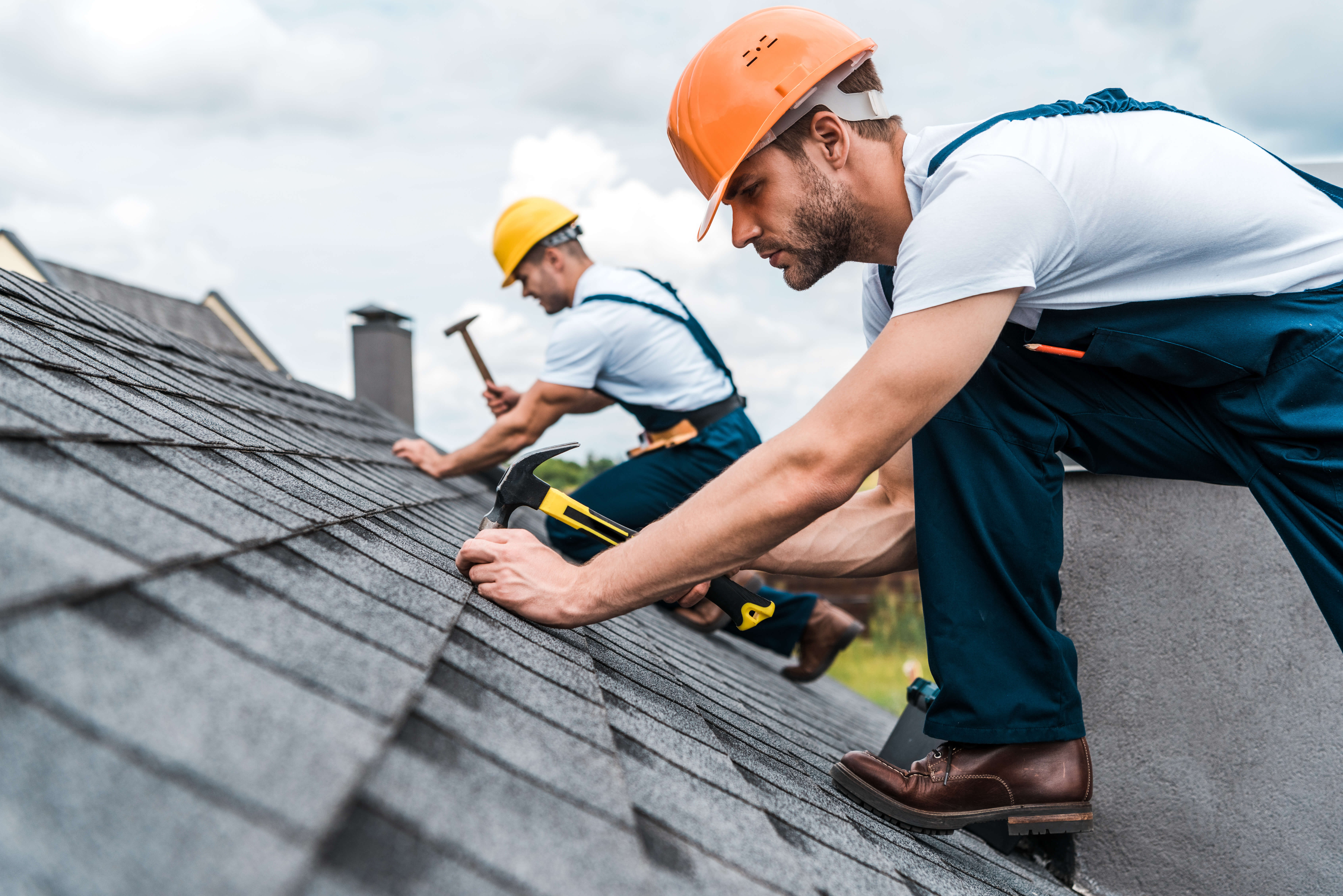 Roofing contractors installing shingles on a new home, representing insurance discounts available for homeowners who work with accredited builders.