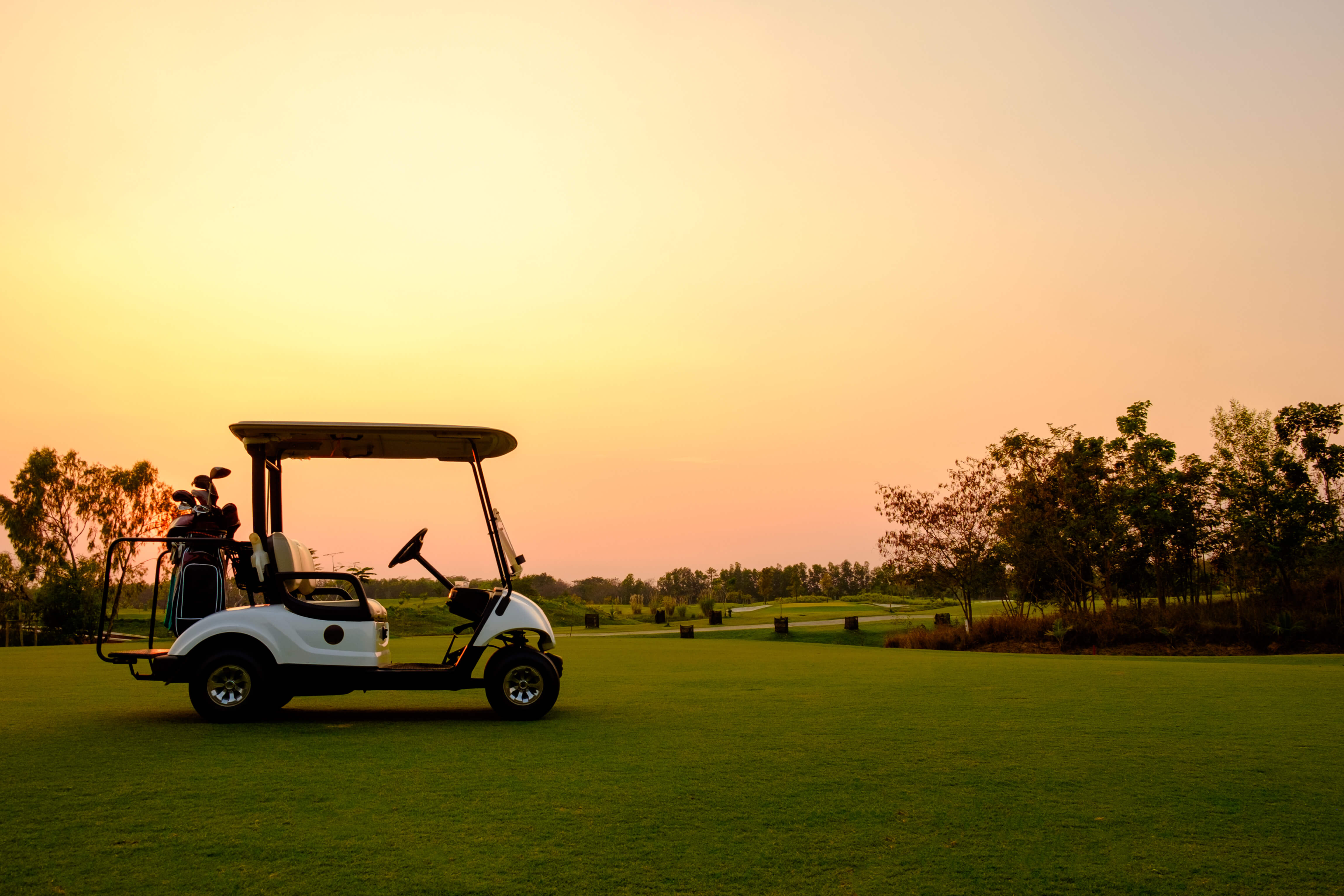Golf cart parked on a scenic golf course at sunset, representing protection and peace of mind with golf cart insurance coverage.