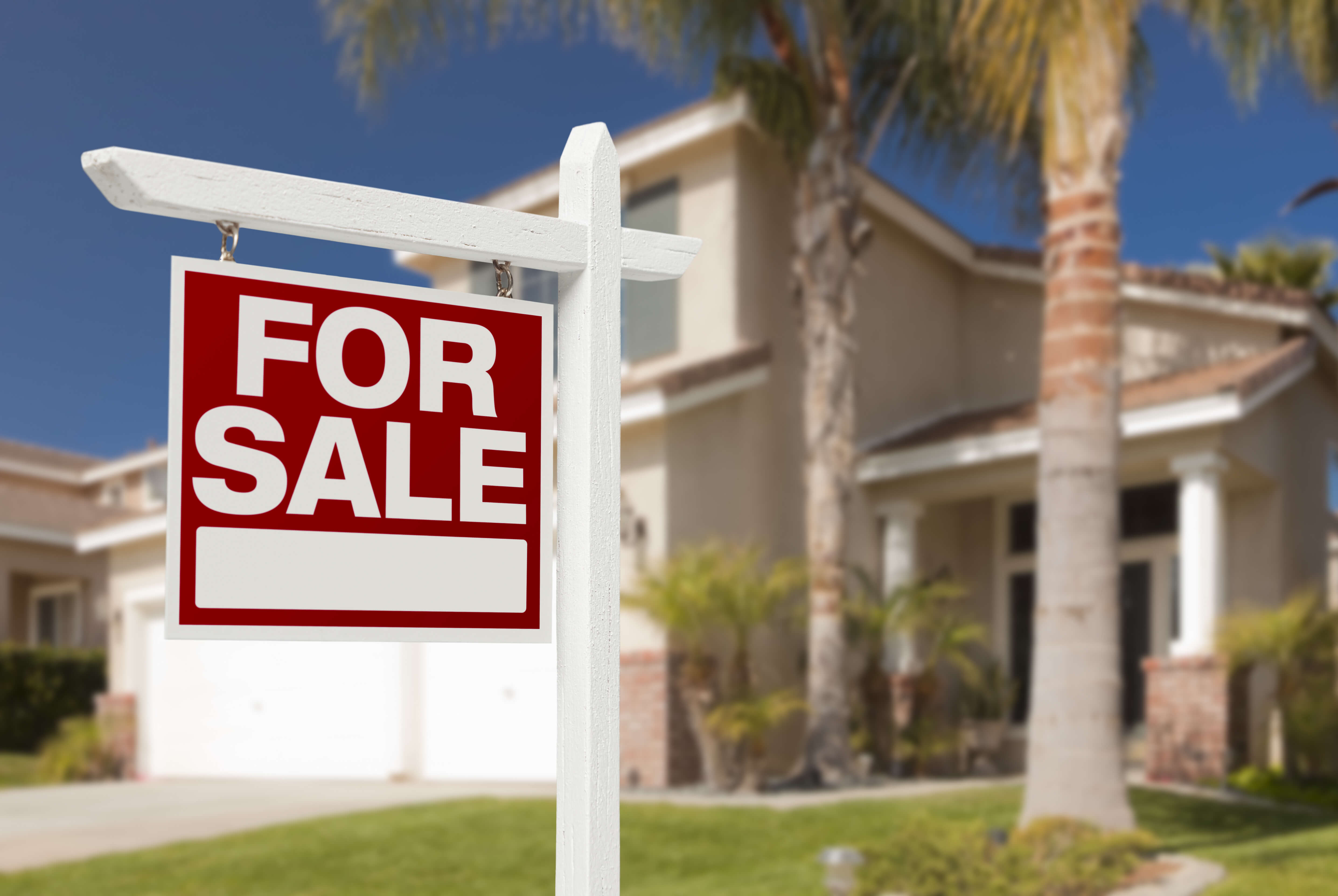 For Sale sign in front of a house with palm trees, representing homebuying resources and the importance of protecting your new investment with homeowners insurance.