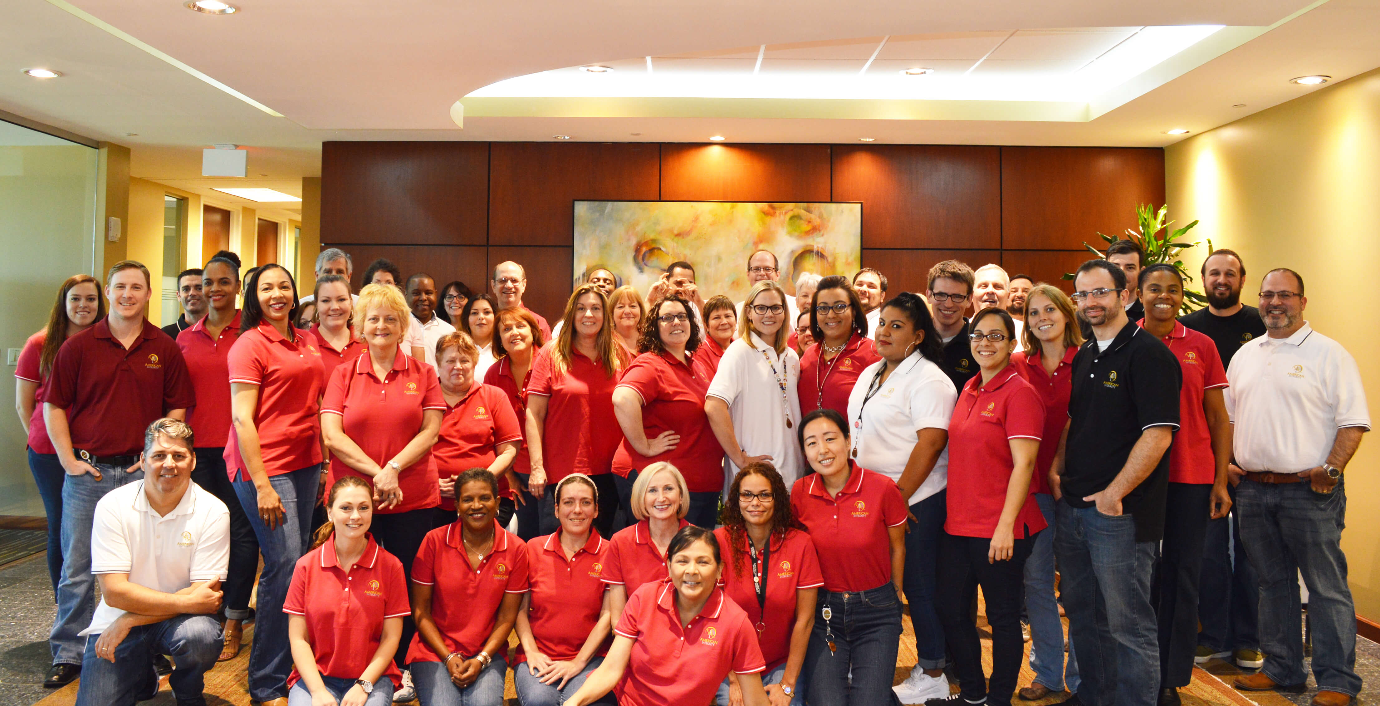 Picture of American Integrity employees in the front lobby wearing matching red polo shirts