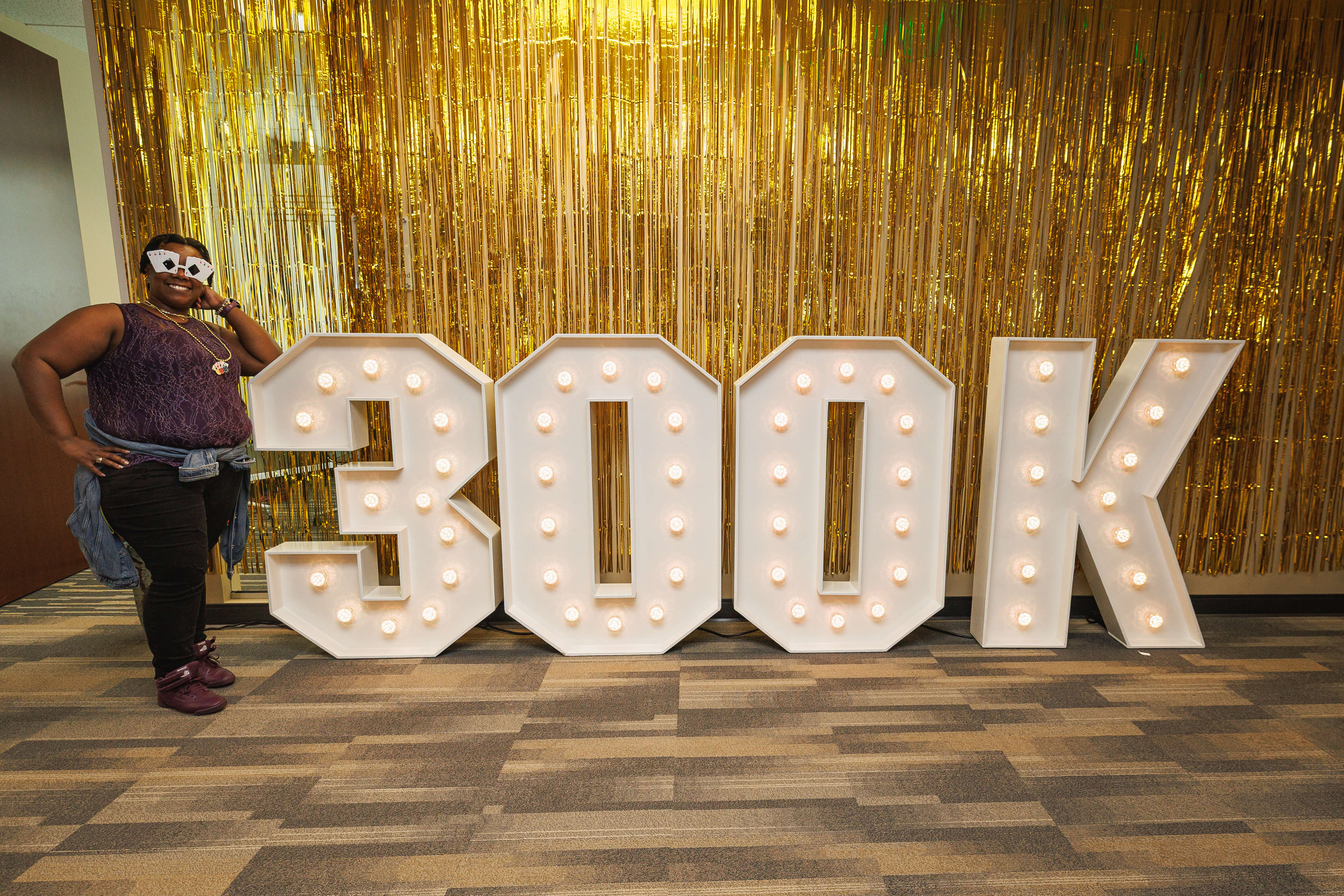A member of our client services team posing in front of a 300K sign in celebration of serving 300,000 policyholders